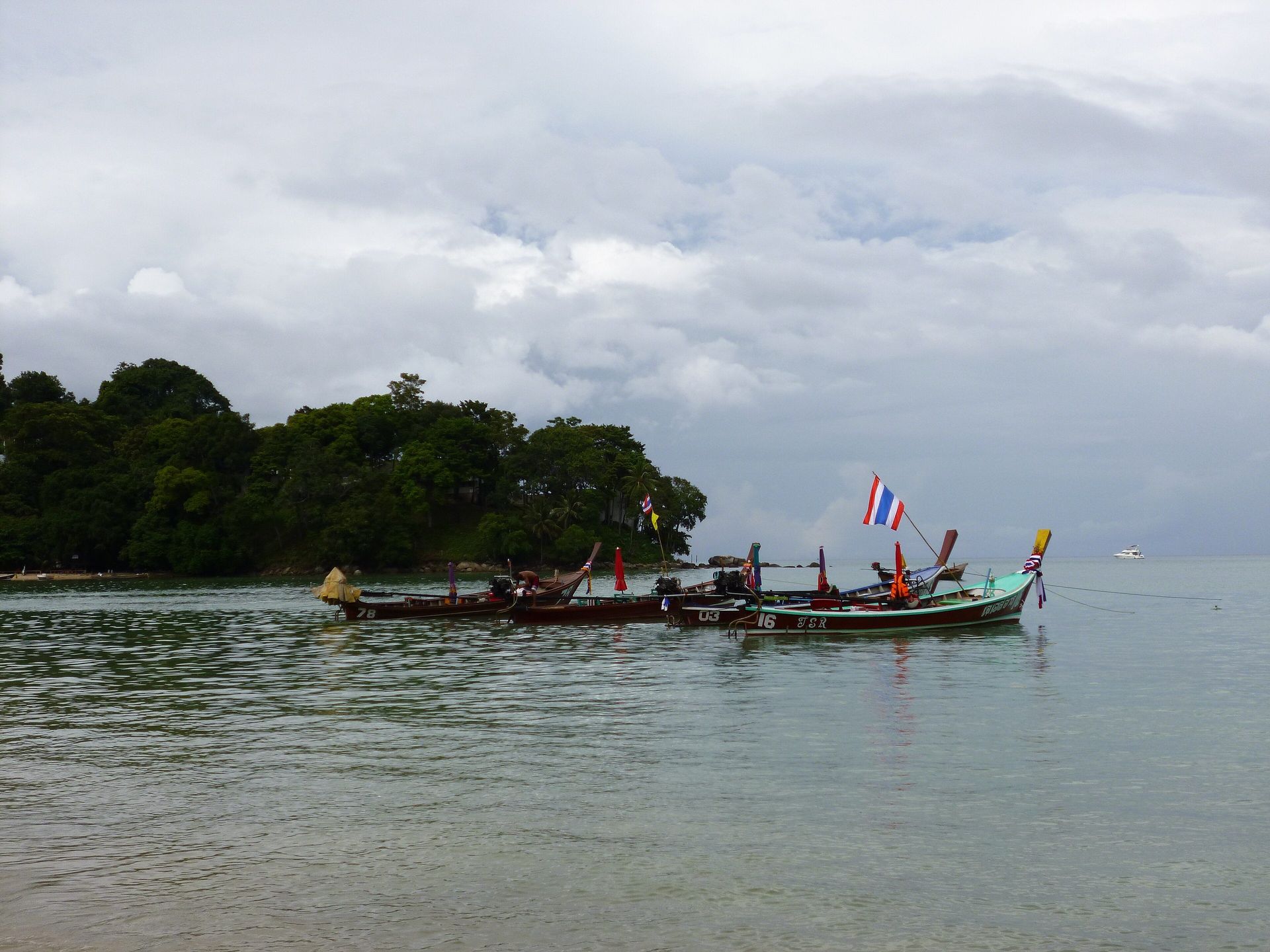 A traveller overlooks a Phuket beach, resort terrace, and longtail boat.
