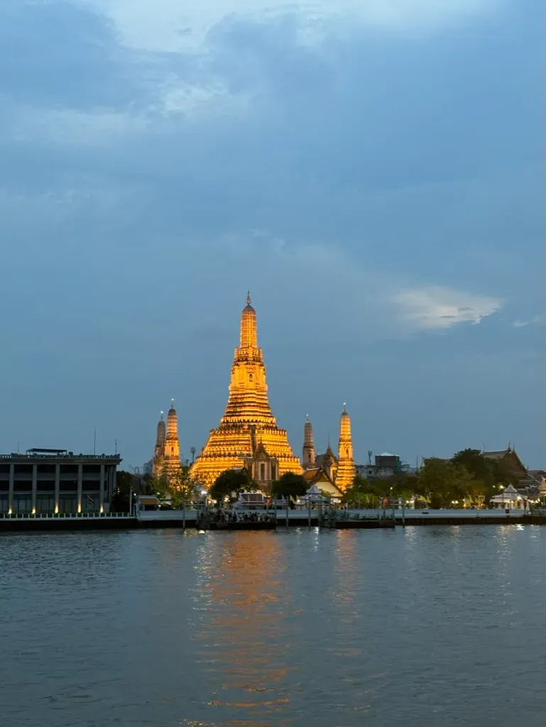A couple plans a Thailand trip with a map, notebook, laptop, and coffee.
