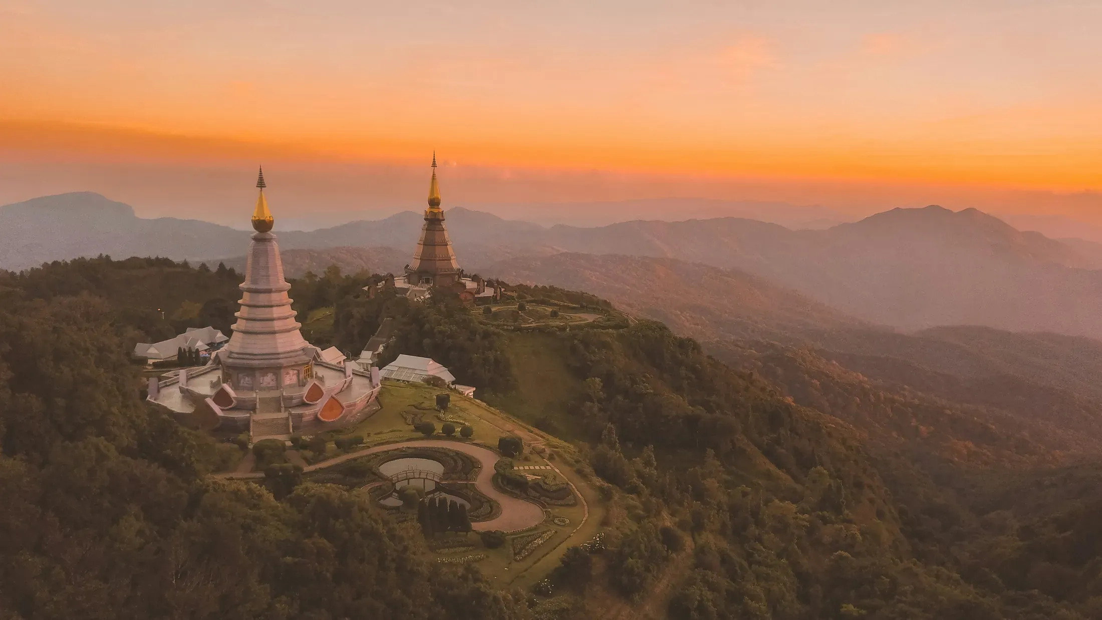 One traveller sits at a garden café table with Northern Thai food, a folded towel, and a distant temple roof.