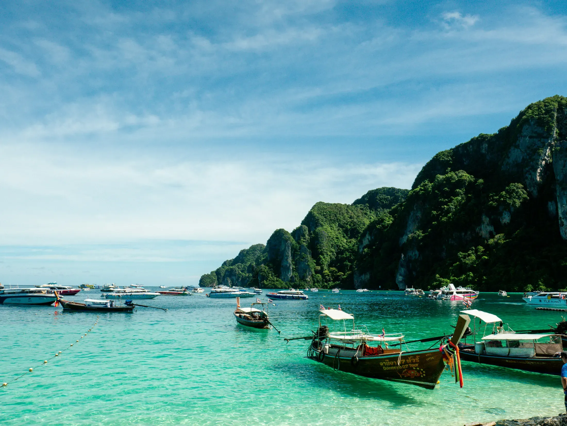 A travel designer plans a Phuket trip with a couple at a desk.