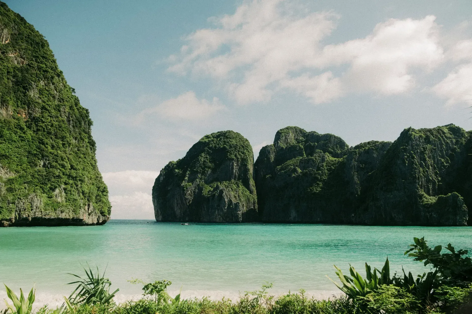 A traveller reviews a Thailand beach itinerary beside a map and laptop.