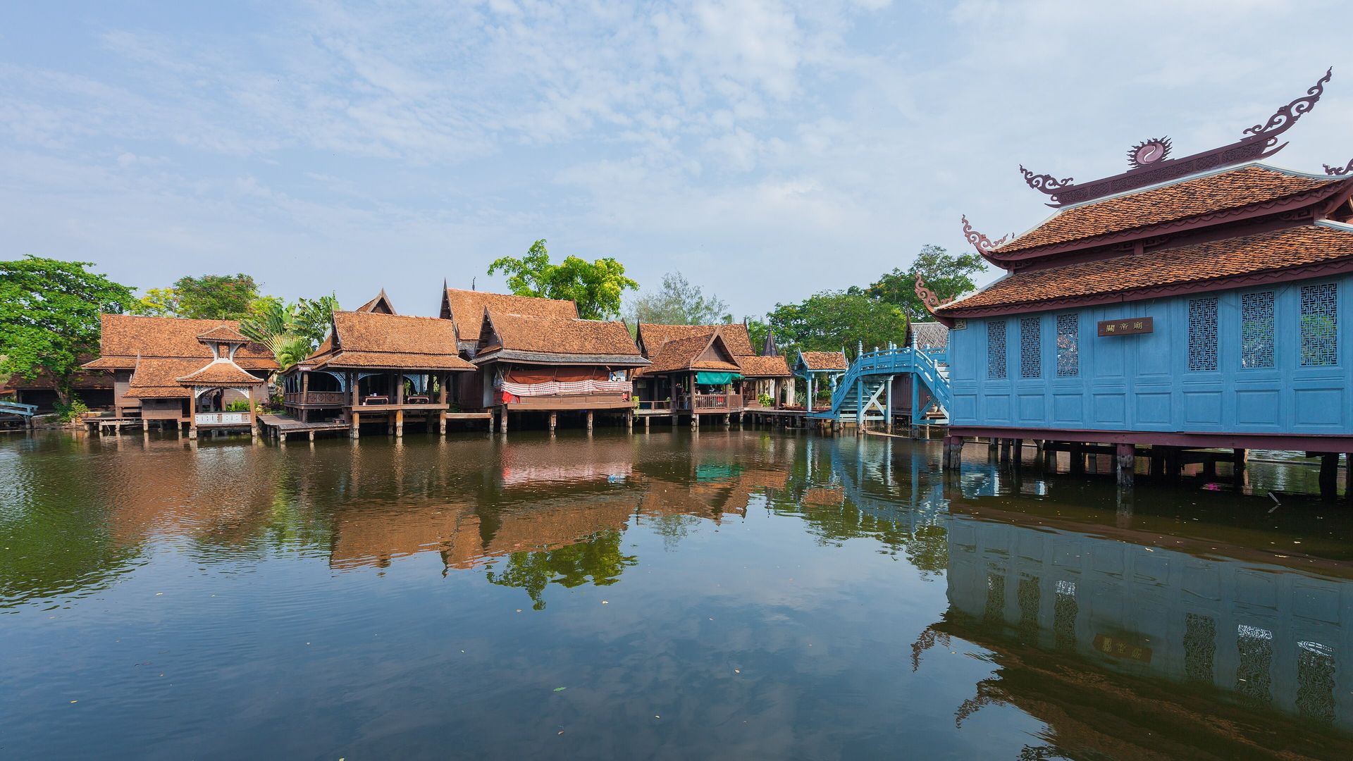 A traveller reviews a Thailand map, notebook, and phone at a warm planning desk.