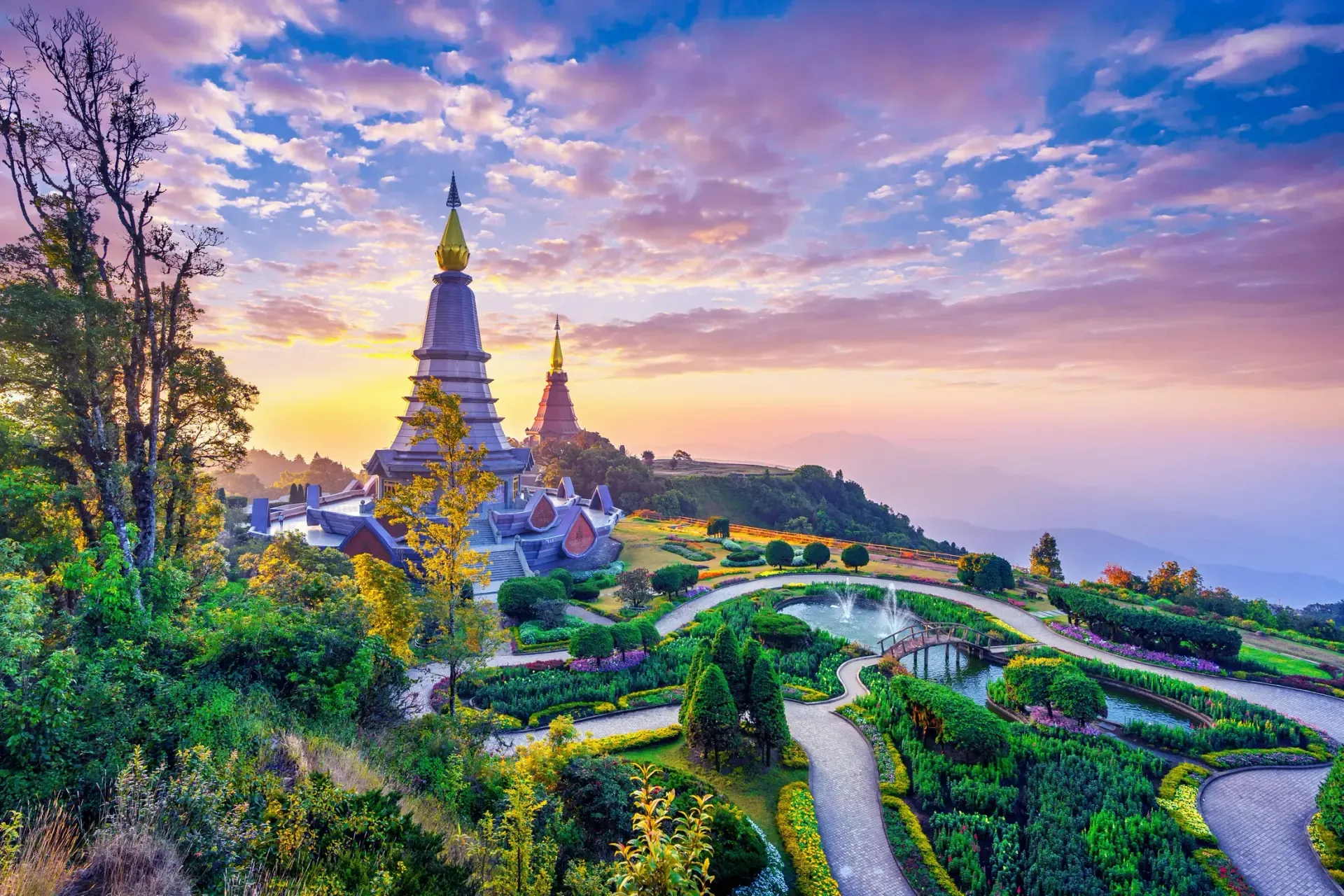 A traveller plans a Thailand trip at a hotel desk beside a blurred map and rainy windows.